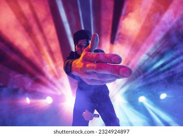 Rap performer. Young talented, artistic man making performance at nightclub, singing over multicolored neon flashlights. Concept of music, performance, art, talent, nightlife, joy, party, lifestyle