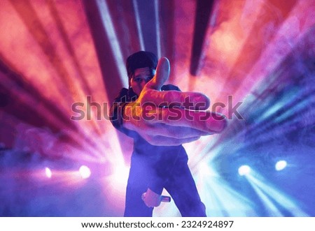 Rap performer. Young talented, artistic man making performance at nightclub, singing over multicolored neon flashlights. Concept of music, performance, art, talent, nightlife, joy, party, lifestyle