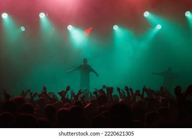 Rap singer performing on concert in music hall. Silhouette of rapper singing on stage in night club. Popuar hip hop music festival. Crowd of fans partying on dance floor