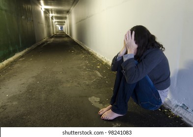 Rape Victim Sad Homeless Woman Sits On The Floor Of A Dark Tunnel. Sexual Assault Concept. Real People. Copy Space