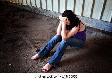 Raped Woman Sitting On The Floor Of An Empty Warehouse - Concept Photo Of  Sexual Assault And Woman Sex Victim. Real People . Copy Space