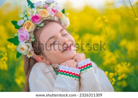 Rapeseed field and dreaming girl with flower chaplet, ethnic folklore dress with traditional Bulgarian embroidery 