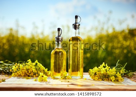 Rapeseed oil bottles (canola) on background rape field 
