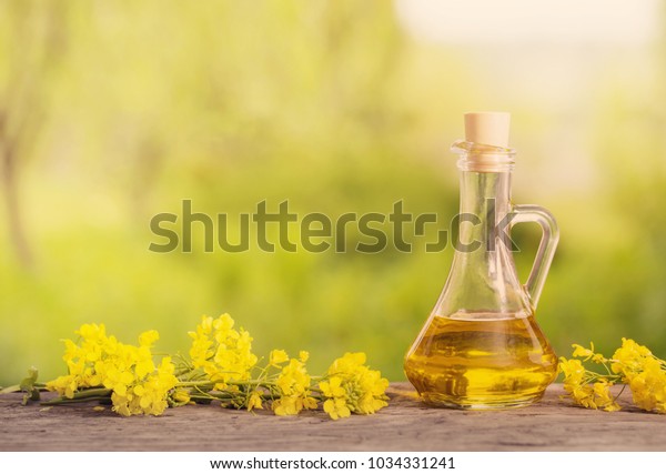 rapeseed\
oil (canola) and rape flowers on wooden\
table