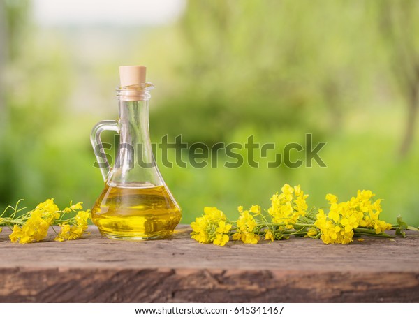 rapeseed\
oil (canola) and rape flowers on wooden\
table