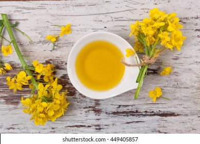 Rapeseed Oil And Flowers On Wooden Background, Top View.