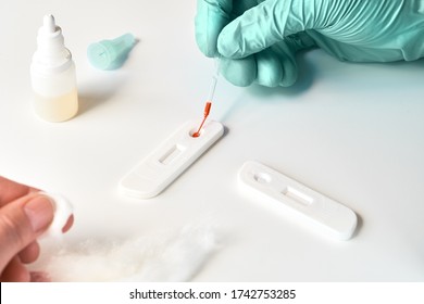 Rapid COVID-19 test for detection of specific antibodies IgM and IgG to novel corona virus SARS-CoV-2 that cause Covid-19. Medic pipettes blood taken from patient finger with pipette on the test.