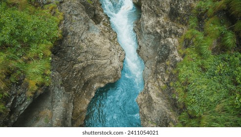 Rapid flow of a mountain river in a deep stone gorge, Austria. Lammerklamm hiking route. Spring clear water in ravine. Top down view.
