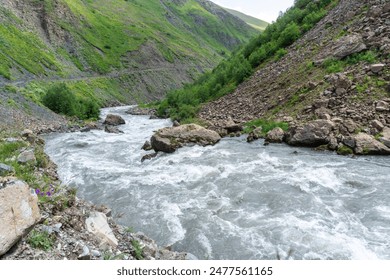 The rapid flow of the Terek River through large stones in a canyon among the rocks