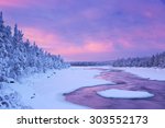 A rapid in a river in a wintry landscape. Photographed at the rapids in the Muonionjoki river in Finnish Lapland at sunrise.