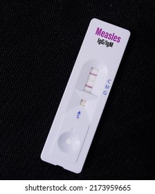 Rapid test cassette or device for Measles IgG and IgM test, show positive result with black background.