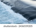 Rapid water flow over barrier, river overflow over dam close up with splash and foam, abstract landscape pastel blue