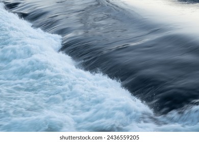 Rapid water flow over barrier, river overflow over dam close up with splash and foam, abstract landscape pastel blue - Powered by Shutterstock