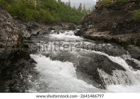Rapids on a mountain stream. Cloudy landscape, Grayling creek on the Putorana plateau.