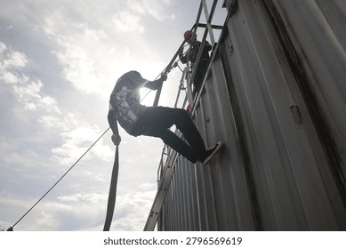  Rappelling training exercise involving several individuals on a large, corrugated metal structure container.
