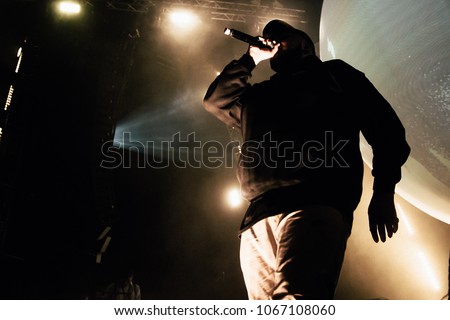 Rapper in hoody with microphone on the stage. 
