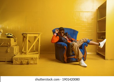 Rapper posing in chair in studio with yellow tones