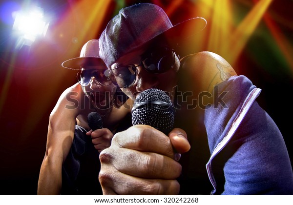 Rappers\
having a hip hop music concert with microphones.  The arrogant\
musician is having a concert in a nightclub. \

