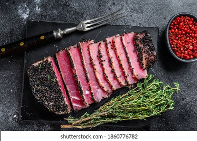 Rare Ahi Tuna Steak Slices With Fresh Herbs On A Cutting Board. Black Background. Top View