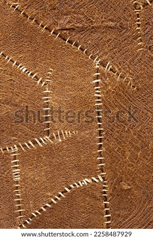 Rare brown cloth sewn with white string. fabric background texture