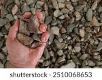 Rare earth (earths) ore, partially closed hand. Critical minerals, used for permanent magnets, aerospace alloys, specialty glass, electronic equipment, hybrid and electric vehicles, wind turbines