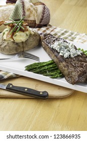 Rare New York Strip Steak On Asparagus Topped With Bleu Cheese With Bread And Twice Baked Potato