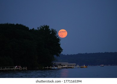 Rare red buck full moon appears over green lake, wisconsin during 4th of july 2020 american independence day holiday. 