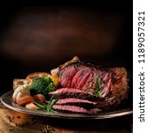 Rare roast beef meal with organic root vegetables and traditional Yorkshire pudding and roast potatoes. Shot against a dark rustic background with generous accommodation for copy space.