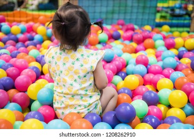 Rare Shot Of Little Girl Having Fun In Ball Pit With Colorful Balls. Child Playing On Indoor Playground. Asian Kid In Ball Pool.