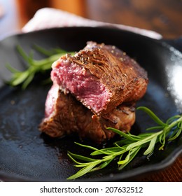 Rare Steak Cut In Half On Iron Skillet With Rosemary