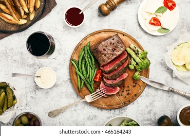 Rare Steak With Side Dish Of French Beans And Glass Of Red Wine On A Wooden Board, Top View