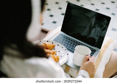 Rare View Of Beautiful Young Asian Woman Sitting Next To Her Bed Using Her Laptop And Enjoy Breakfast At Home. Small Business Owners Are Checking Orders Online. Concept For Freelancer Lifestyle.