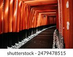 A Rare Winter snow at Torii Gate Tunnel at Fushimi Inari Shrine in Kyoto Japan. Orange and black beams with traditional Japanese Lanterns