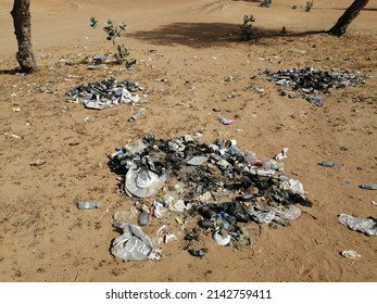 Ras Al Khaimah, United Arab Emirates - April 5, 2022: Burnt trash carelessly strewn in desert sand dunes terrain. Outdoor nature littering concept.