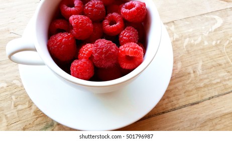 Rasberries In Cup On Wooden Table