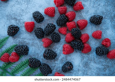 Raspberries and blackberries. Good for diet. Top view. Close-up on blue stone background