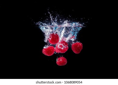 Raspberries Falling Into A Water Black Background