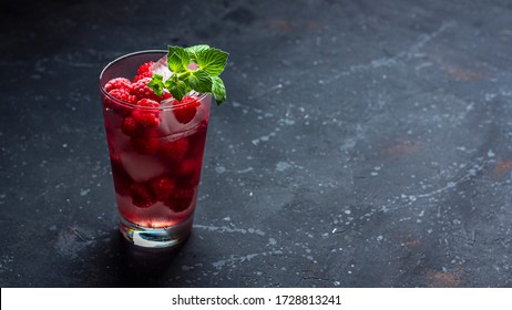 Raspberry alcoholic cocktail with liqueur, vodka, ice and mint on a dark background. Raspberry Mojito. Refreshing cool drink, lemonade or ice tea in a glass. Close up, copy space for text, banner