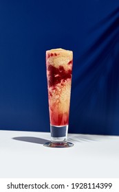 Raspberry And Banana Smoothie Over White And Blue Background. Palm Leaf With Sunshine And Hard Shadow. Fruit Yogurt Or Shake Drink In High Glass. Summer, Healthy, Fresh Drink Concept