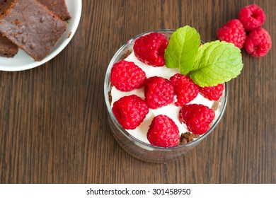 Raspberry And Brownie Parfait On A Wooden Table, Up View.