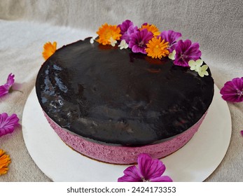 raspberry cake with blackberry jelly frosting. purple and pink colors of the corpus in the shape of a circle. decoration of meadow flowers. marigold and mallow in a bright orange composition