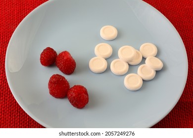 Raspberry Candy Pieces With Fresh Raspberries On Blue Plate On Red Tablecloth