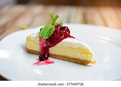 Raspberry cheesecake with fresh cherry on white plate.
