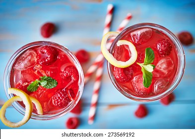 raspberry cocktail with lemon and mint shot from overhead view on rustic table top