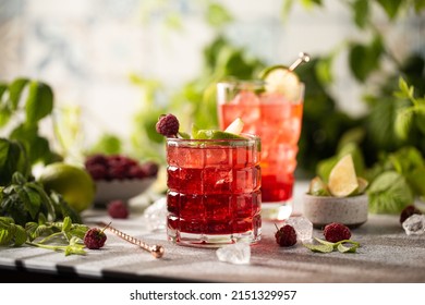 Raspberry cocktail with lime,mint,ice cubes and fresh berries on grey background with juicy summer greenery.Beautiful photo of refreshing drink. - Powered by Shutterstock