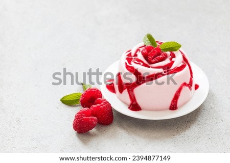 Raspberry Cream dessert, Panna Cotta in the shape of a rose, with raspberry sauce, on a plate. Copy space	