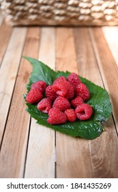 Raspberry fruits on a leaf , on rustic wooden table. Superfood rich in fiber and vitamins.