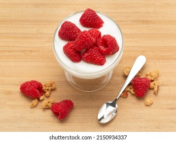 Raspberry Granola Yogurt Parfait With Spoon On Wooden Cutting Board