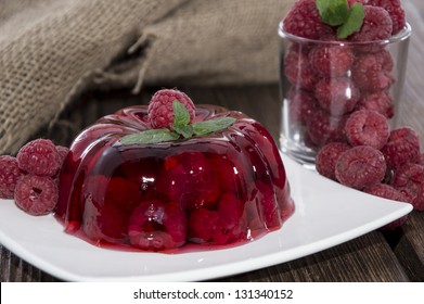 Raspberry Jello with fresh fruits on wooden background