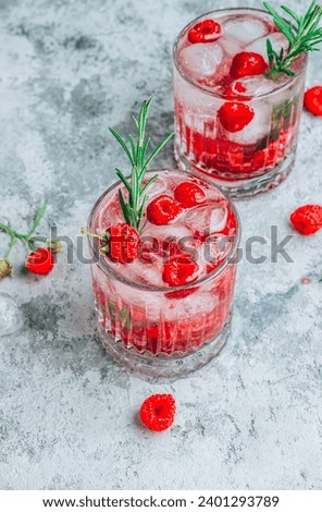 Raspberry lemonade in a glass with ice and fresh rosemary on a concrete background. Selective focus